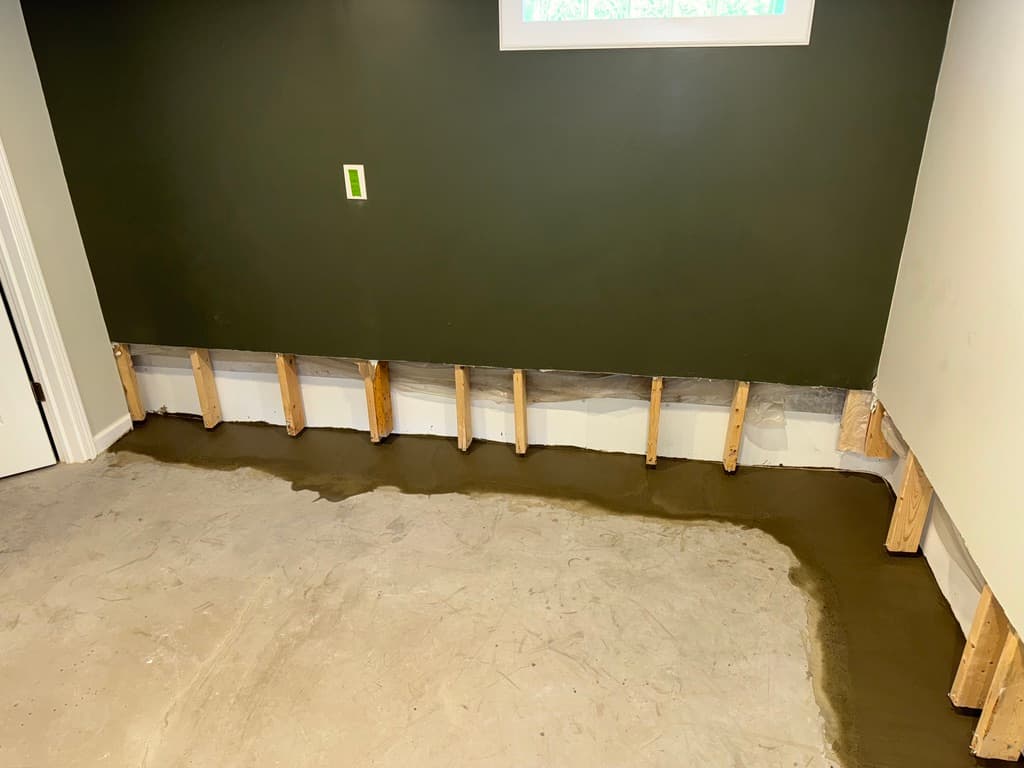 Active interior drain channel along a basement wall with wet concrete fill