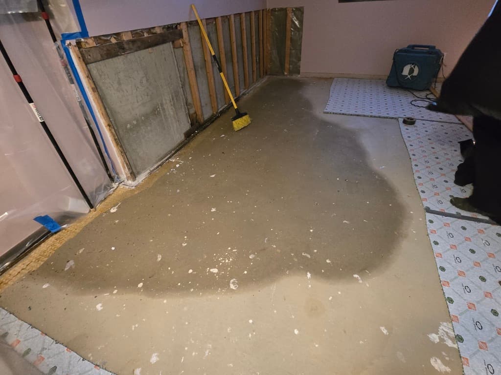 Mid-installation interior French drain with fresh concrete fill along the wall-floor joint
