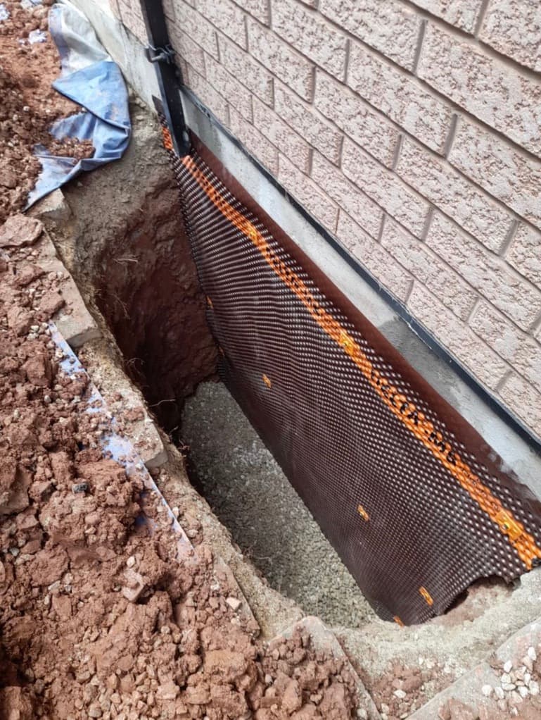 Egress window install with dimple board membrane and gravel drainage against the foundation